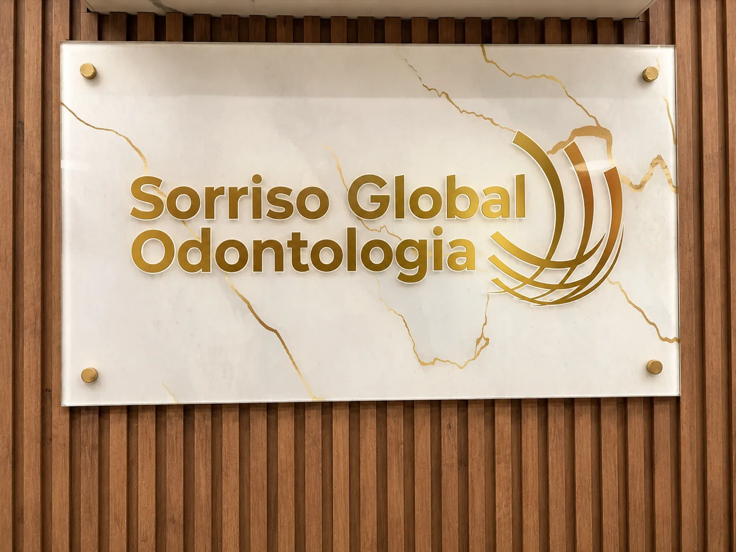 Placa dourada da Sorriso Global sobre painel de madeira